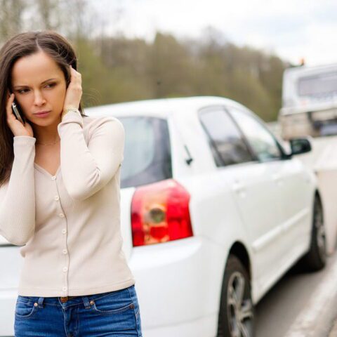 A woman on the side of the road talking on her phone.