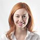 A woman with red hair and white shirt smiling.